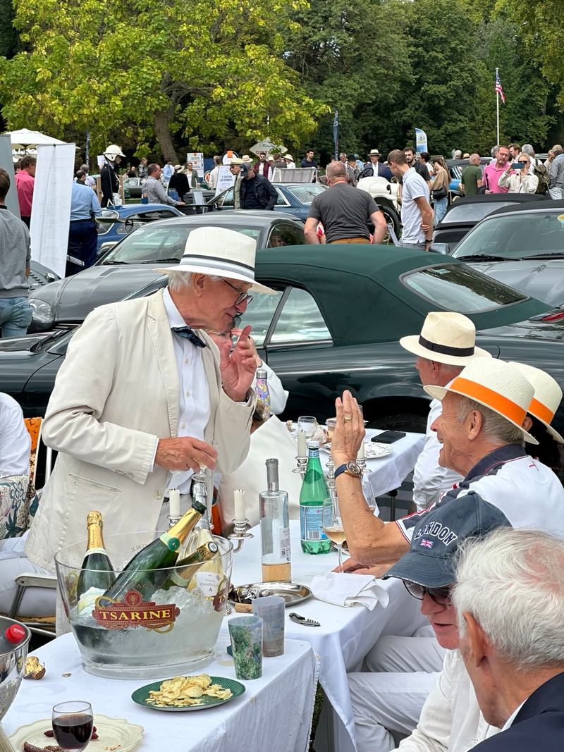 Club members in panama hats lunching at a white-clothed table with champagne.
