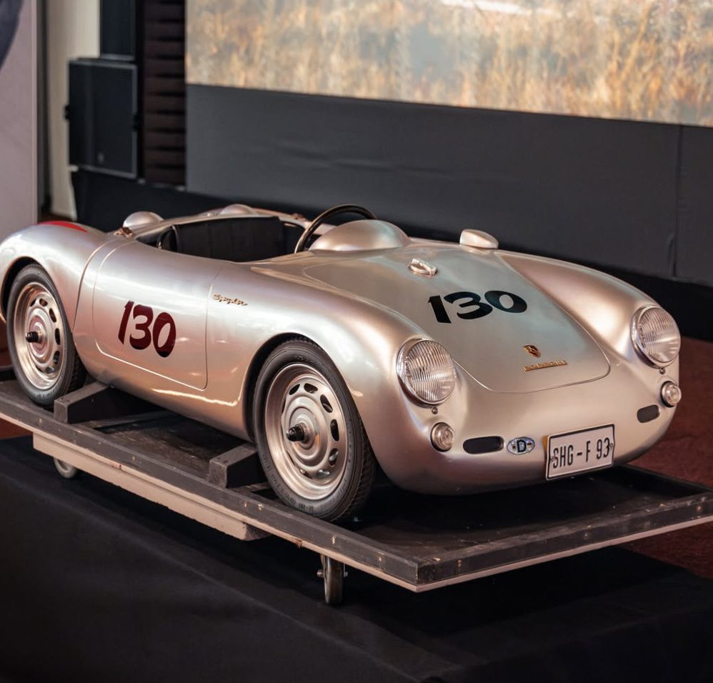 Un coche infantil Porsche 550 Spyder plateado a media escala con el dorsal 130